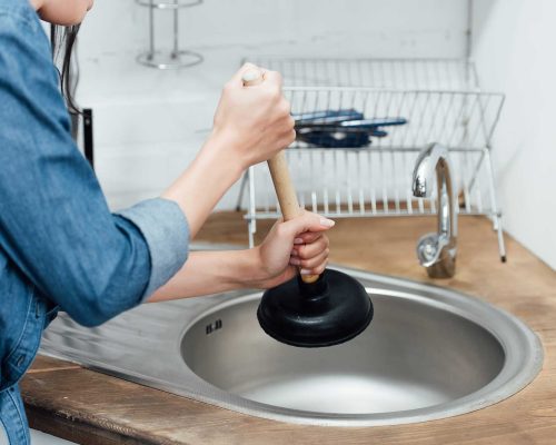 partial-view-of-woman-in-denim-shirt-using-plunger